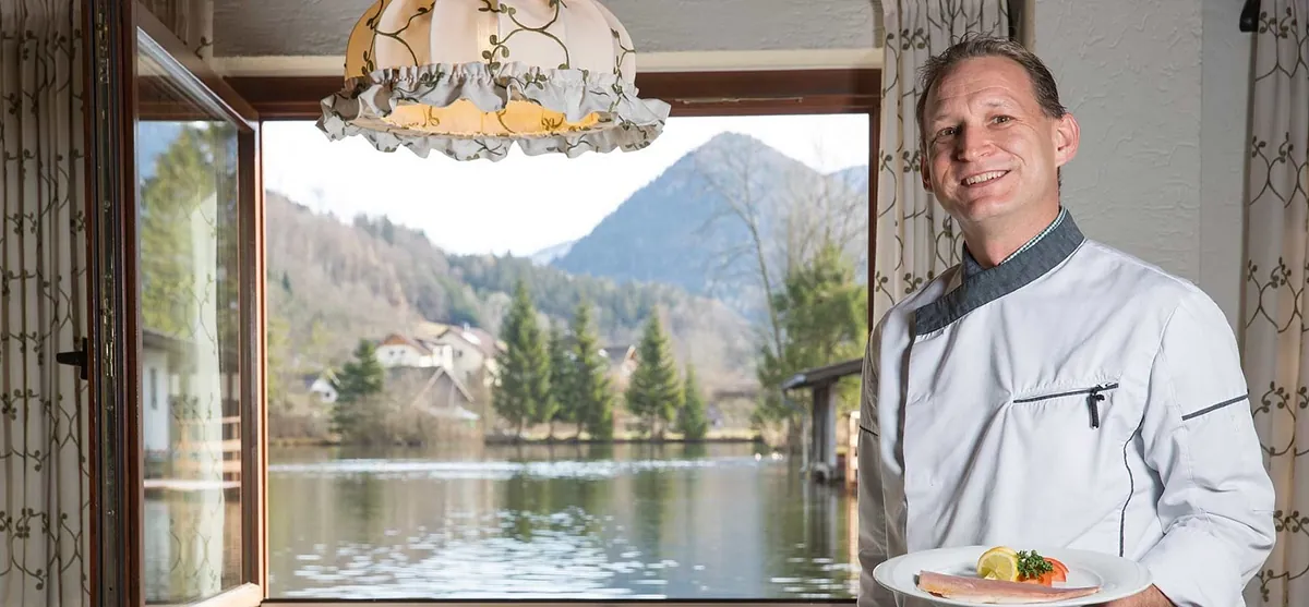 Koch mit zubereiteter Forelle vorm Weiher im Forellenhof - Wieselmühle in Grünau im Almtal